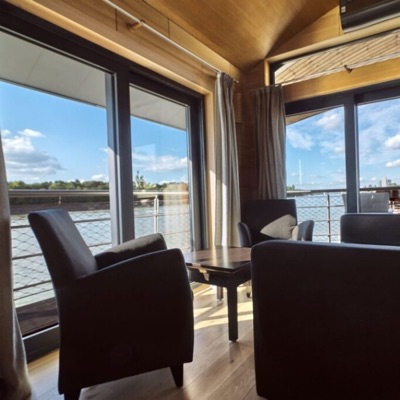 Lounge corner with armchairs in front of floor-to-ceiling windows overlooking the Danube