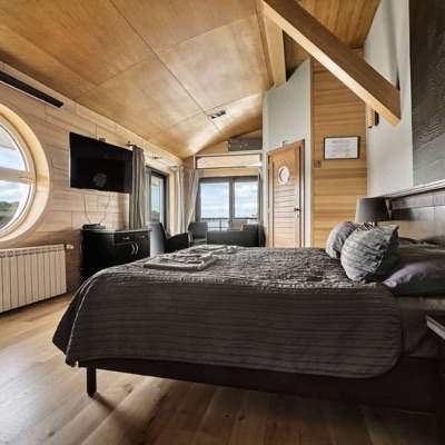 Wood-panelled bedroom with a large round window, TV and double bed