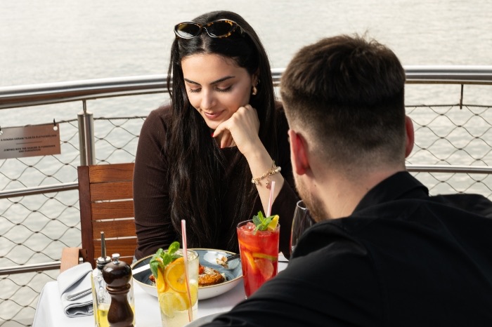 Egy pár limonádét iszik és vacsorázik a hajó teraszán
